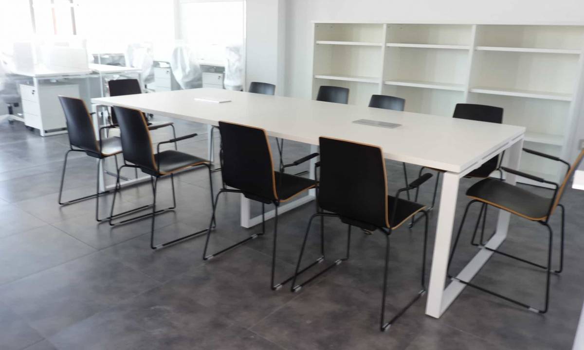 Altia_Galeria_Sala de reuniones con sillas negras y mesa blanca para cooperacion y zona de almacenaje