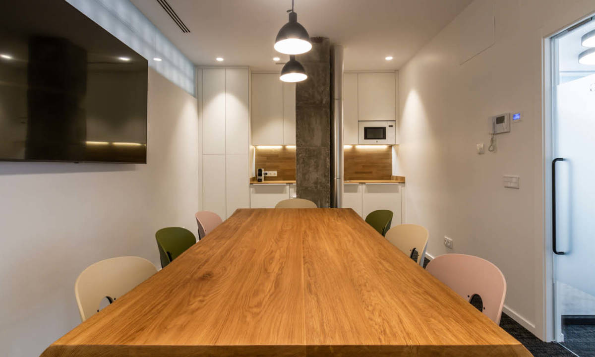 Zona de office con mesa grande de madera y sillas de colores en habitacion