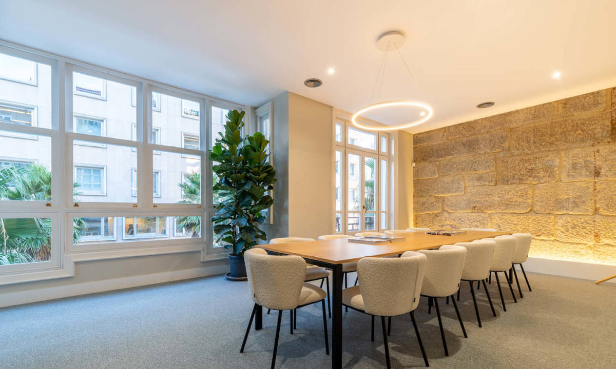 Sala de reuniones con amplios ventanales y elementos estructurales históricos diseñada y equipada por Sutega