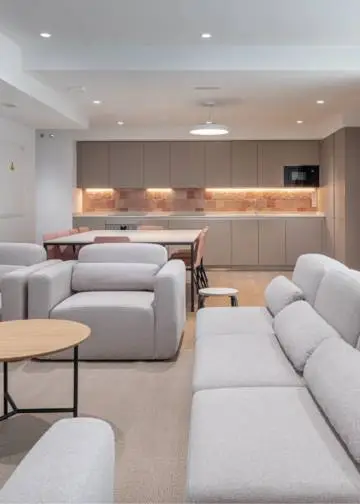 Salón común en edificio compartido con cocina, mobiliario de soft seating y vegetación