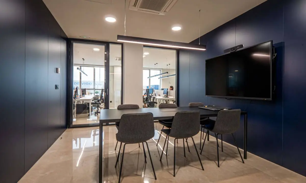 Sala de reuniones con monitor de gran formato y mobiliario estándar ergonómico