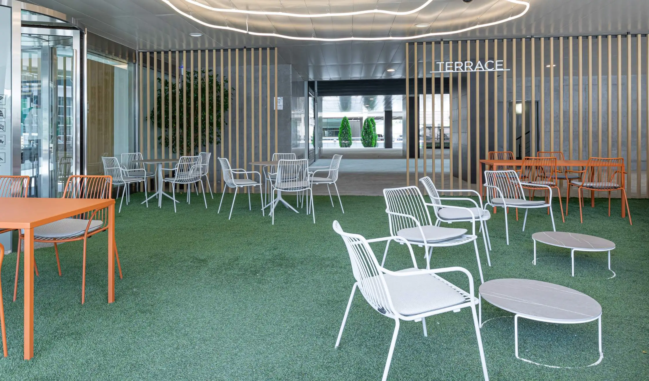 Mobiliario de exterior en blancos y naranjas en terraza de oficina en Madrid