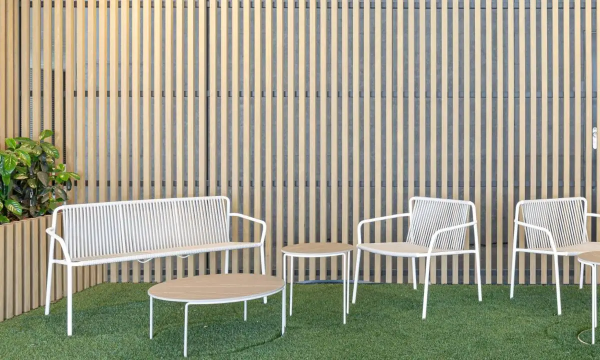 Espacio exterior de oficina con mobiliario en blanco y laminado de madera en la pared