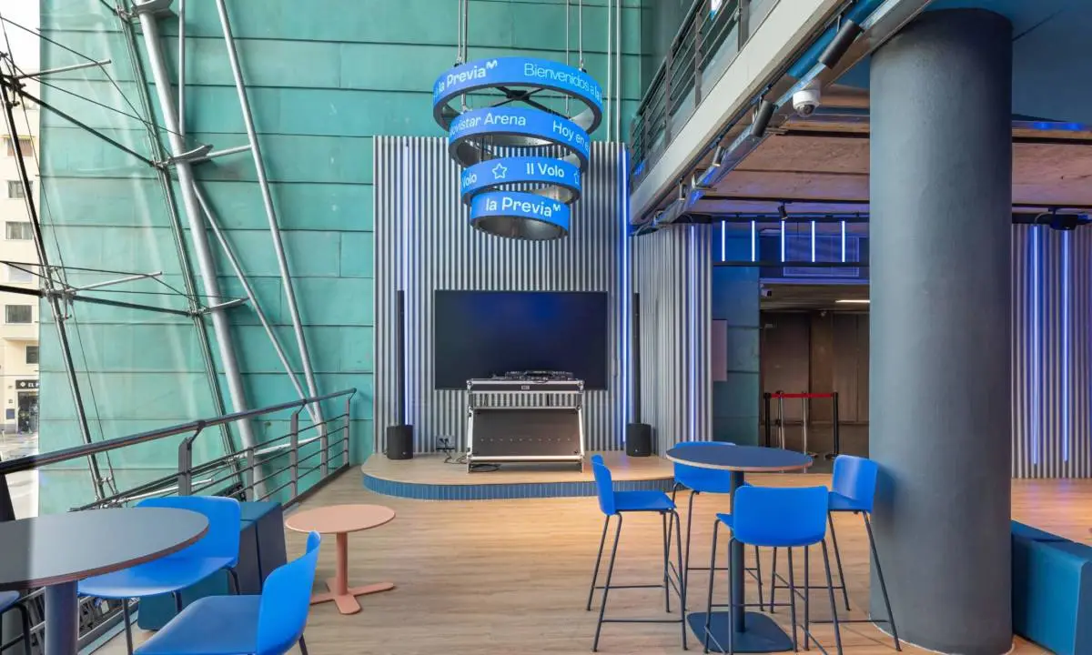Zona común con monitor, taburetes, mesas altas, rotulación en recinto de conciertos en Madrid