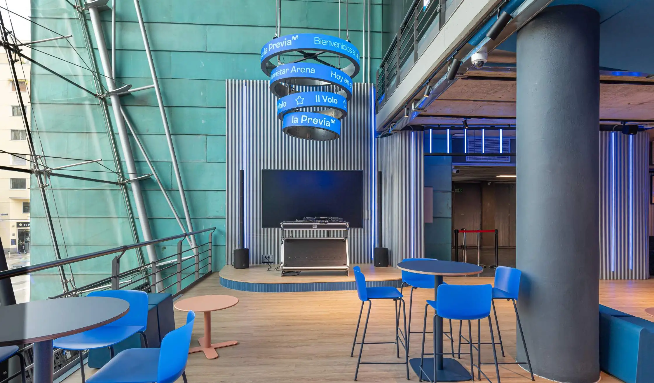 Zona común con monitor, taburetes, mesas altas, rotulación en recinto de conciertos en Madrid